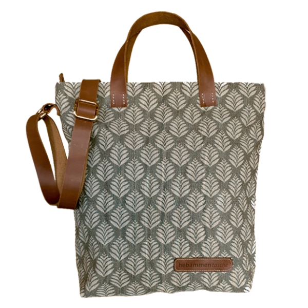 Hebammentasche "Bonnie" in Grau. Die kurzen und langen Henkel bestehen aus einem braunen Leder, sowie die vordere Aufschrift "hebammentasche". Die Tasche ist mit einem Blätter-Print verziert.