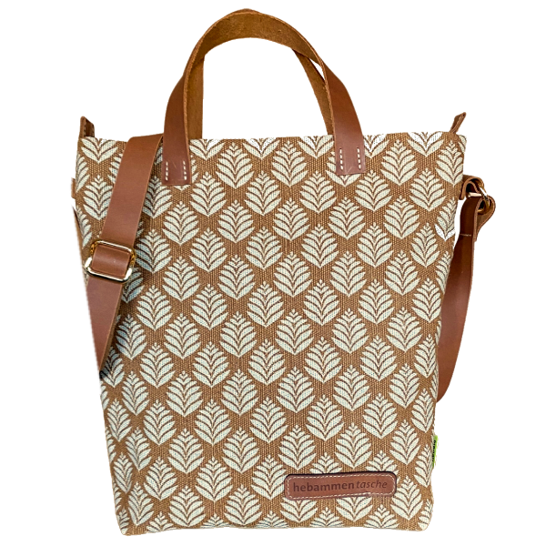 Hebammentasche "Bonnie" in Ocker. Die kurzen und langen Henkel bestehen aus einem braunen Leder, sowie der vordere Aufdruck "hebammentasche". Die Tasche ist verziert mit einem Blätter-Print.