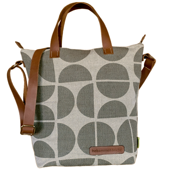 Die Hebammentasche "Pop" in grau ist mit kurzen und langen Lederhenkeln ausgestattet. Die Vorderseite ist mit einer Lederaufschrift "hebammentasche" und einem halbkreisartigen Muster verziert.
